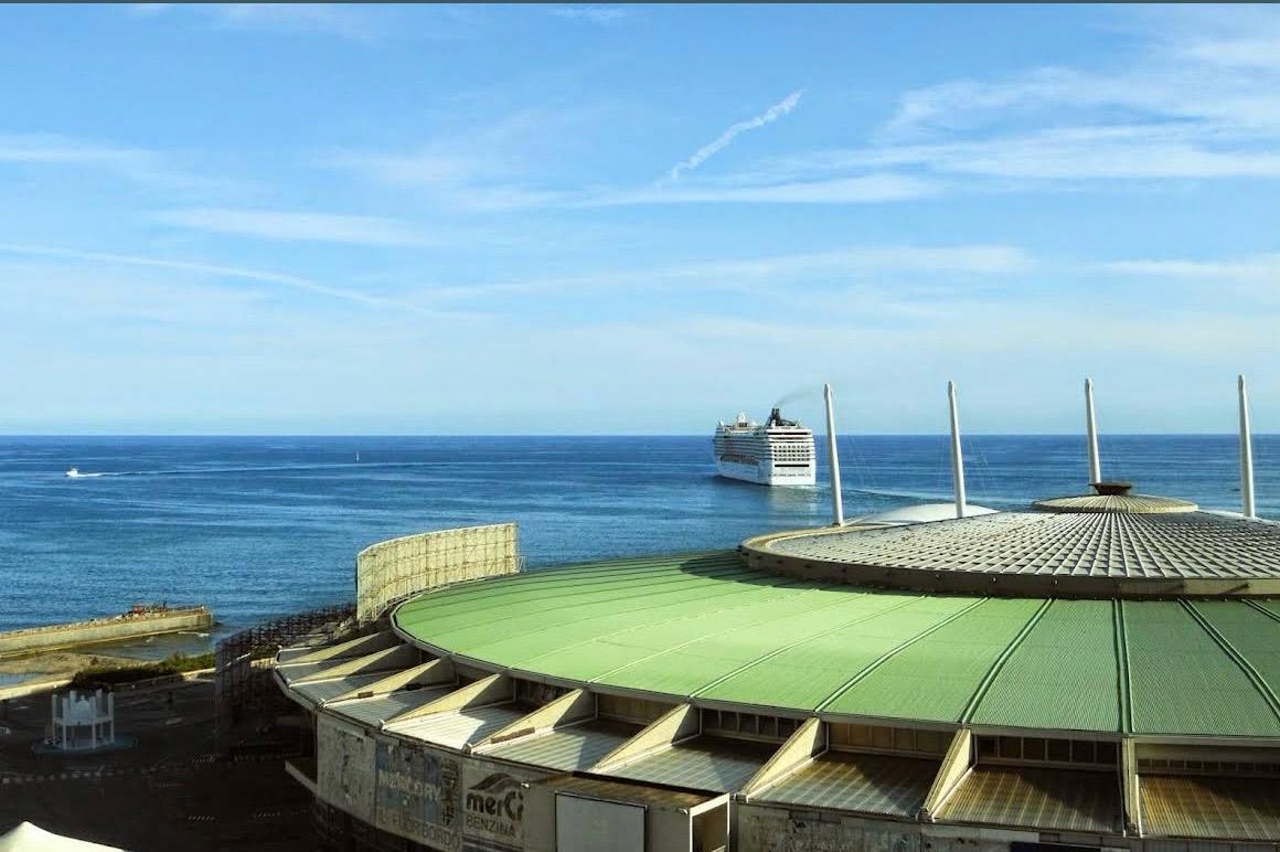 Panorama sul mare di Genova, con una nave e il padiglione della Fiera in primo piano